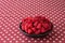 Luscious fresh picked raspberries in a large black ceramic bowl on a background of white stars on a field of red