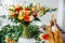 A lush bouquet in the boho style on a table littered with leaves and tools in the florist's workshop