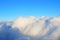 Lush cumulus clouds swim across the blue sky, view from the porthole airplane