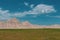 Lush, emerald green grass field with sand-covered hills in the background