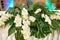 Lush floral arrangement of orchids and monstera leaves on wedding table. Wedding presidium in restaurant, copy space.