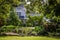 Lush garden with elephant ears and two story house in background with landscaping sail and trees - Selective focus