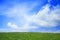 Lush, green landscape with blue sky and clouds.