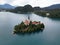 Lush island with a white a church, surrounded by lake water and lush green trees in the background