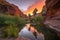 lush oasis surrounded by fiery canyon sunset, with palm trees and water in the background