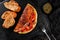 Lush omelet with meat, vegetables, cheese and herbs on black slate over dark background. Healthy breakfast. Top view, flat lay