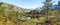 Lush rocky wilderness with greenery of wild grass and trees surrounding a pond with a blue sky copy space background