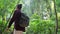 Lush tropical rainforest and backpacker lady passing camera