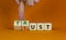 Lust or trust symbol. Businessman turns wooden cubes and changes the words `lust` to `trust`. Beautiful orange table, orange