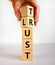 Lust or trust symbol. Businessman turns wooden cubes and changes the words `lust` to `trust`. Beautiful white table, white