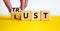 Lust or trust symbol. Businessman turns wooden cubes and changes the words `lust` to `trust`. Beautiful yellow table, white