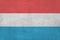 Luxembourg flag depicted in bright paint colors on old relief plastering wall. Textured banner on rough background