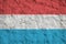 Luxembourg flag depicted in bright paint colors on old relief plastering wall. Textured banner on rough background