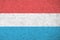 Luxembourg flag depicted in bright paint colors on old relief plastering wall. Textured banner on rough background