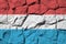 Luxembourg flag depicted in paint colors on old stone wall closeup. Textured banner on rock wall background