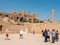 Luxor, Egypt - October 3, 2021: People walk and take pictures along the ancient ruins of the Karnak Temple. The guide tells a