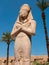 Luxor, Egypt - October 3, 2021: View of the statue of Ramses II in the Karnak temple against the background of the blue sky and