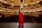 A luxurious actress in a red dress sings on stage with a microphone in her hands