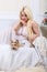 Luxurious blonde woman in a white dress with a dog pekingese