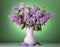 Luxurious bouquet of fragrant lilac in vase on green