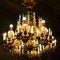 Luxurious interior chandelier has lit candles and a dark background. Noble candelabra hang from the ceiling