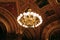 Luxurious interior chandelier with lit bulbs and a dark background. A noble candelabrum with many small patterns hangs