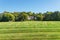 Luxurious large brick single family house surrounded by trees with a large green lawn. Landscape on a summer sunny day