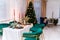 Luxurious New Year interior of the room. The room contains a Christmas tree, corduroy armchairs and a large table. On the table