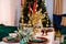 Luxurious New Year table setting. The room contains a Christmas tree, corduroy armchairs and a large table. On the table are