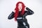 Luxurious plus size woman with Asian face, bright makeup and red curly hair posing in shiny closed long black dress on white backg