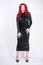 Luxurious plus size woman with Asian face, bright makeup and red curly hair posing in shiny closed long black dress on white backg