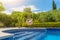 Luxurious pool in the garden of a private villa, hanging chair with pillows for leisure tourists, in summer. Portugal