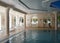 Luxurious pool interior design, sunlight from panoramic Windows, stylish columns and turquoise water