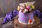 Luxurious Purple cake decorated with a bise, marshmallow, berries and fresh flowers.