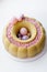 Luxurious round dessert with pink chocolate spheres. Yellow mousse birthday cake with multicoloured sweet sugar balls