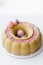 Luxurious round dessert with pink chocolate spheres. Yellow mousse birthday cake with multicoloured sweet sugar balls