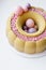 Luxurious round dessert with pink chocolate spheres. Yellow mousse birthday cake with multicoloured sweet sugar balls