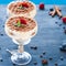 Luxurious tiramisu in cocktail glasses decorated with cocoa powder on a dark background