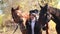 Luxurious young girl walks with two horses in the forest in warm autumn weather.