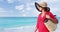 Luxury beach vacation elegant lady walking on beach stroll with beachwear sun hat and straw tote bag wearing red cover