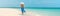 Luxury beach vacation elegant tourist woman walking relaxing in beachwear hat on white sand Caribbean beach. Lady