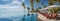 Luxury beachfront escape: panoramic view of resort, pool, beach chairs, and umbrellas