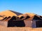 Luxury brown tent camp in Sahara Desert Merzouga, Morocco on a sunny day with sand dunes on background