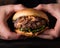 Luxury burger with a brioche bun on black background. Hands grabbing burger