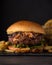 Luxury burger with a brioche bun on black background. Knife in burger
