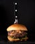 Luxury burger with a brioche bun on black background. Knife in burger