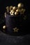 Luxury cake with dark blue cream cheese frosting decorated with golden chocolate stars and spheres. Birthday space themed cake on