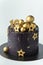 Luxury cake with dark blue cream cheese frosting decorated with golden chocolate stars and spheres. Birthday space themed cake on