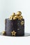 Luxury cake with dark blue cream cheese frosting decorated with golden chocolate stars and spheres. Birthday space themed cake on