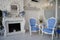 Luxury elegant designer domestic sitting room interior with two blue white rococo armchairs next to fireplace, AI